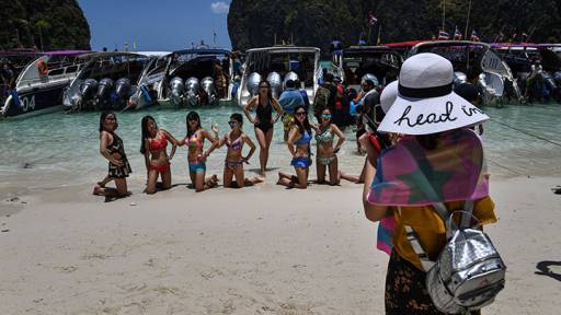 This photo taken on April 9, 2018 shows tourists posing in swimsuits in front of a row of speedboats in Maya Bay, on the southern Thai island of Koh Phi Phi.