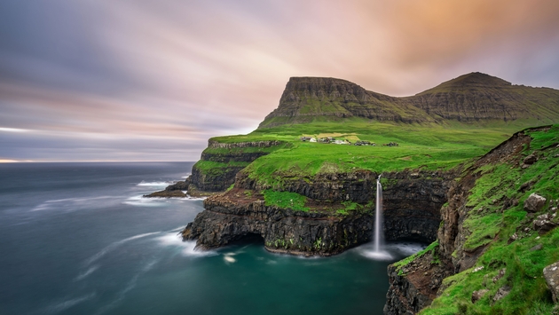 Gasadalur village and its iconic waterfall, Vagar, Faroe Islands, Denmark. Long exposure. (photo via miroslav_1 / iStock / Getty Images Plus)