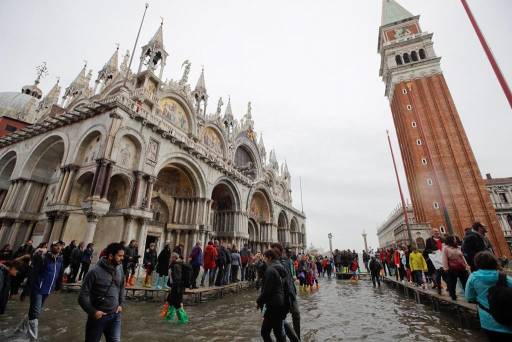 In this Nov. 1, 2018 file photo, tourists walk in flooded St. Mark’s Square in Venice, Italy.